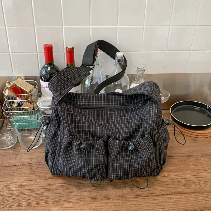 Simples Market black plaid nylon shoulder bag with front drawstring pockets and crossbody strap
