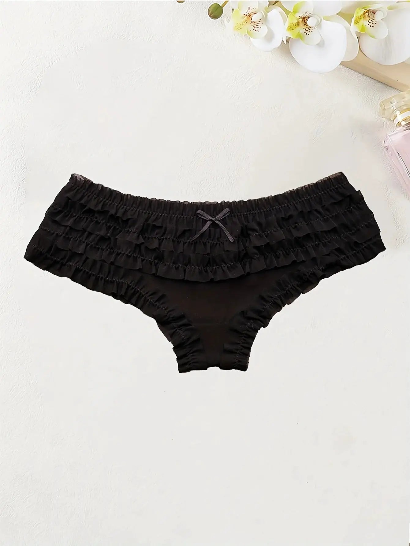 Black lace-trimmed women's low-rise bikini briefs with layered ruffles and bow