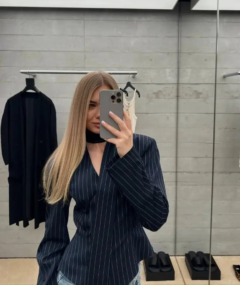 Navy pinstripe blazer worn by a woman in a mirror selfie with long sleeves and V-neck wrap style