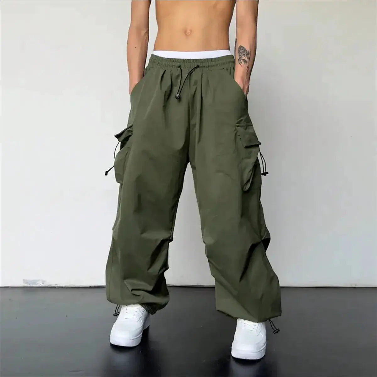 Olive green cargo pants with elastic waist, drawstring hems, and multiple pockets for a baggy streetwear look