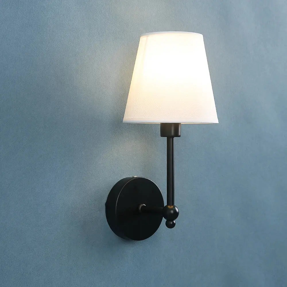 Wall sconce lamp: black metal with round backplate and white fabric shade.