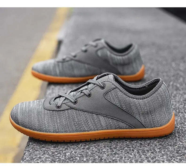 Pair of men's trail running shoes with gray knit upper and orange soles
