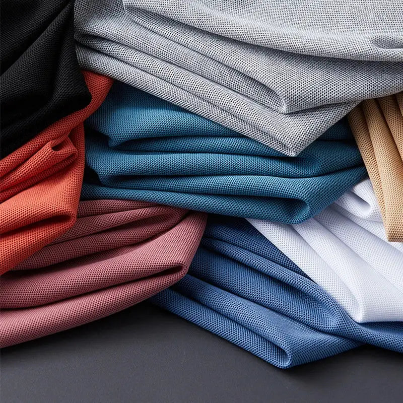 Men's polo shirts by Simples Market in 9 assorted colors, neatly folded in a stacked casual display.