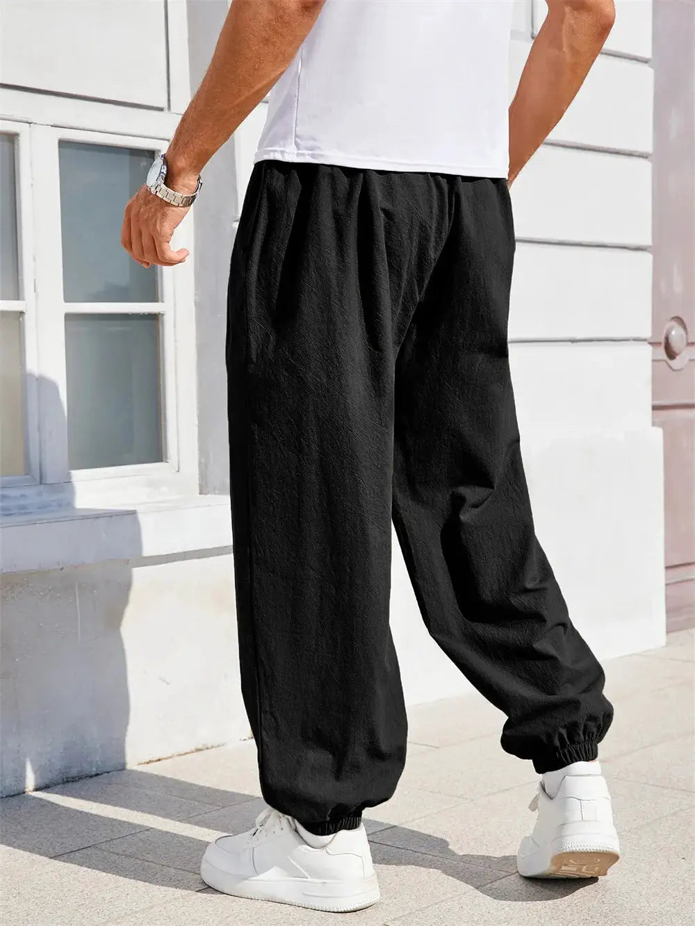 Men's black cotton linen harem pants with a loose fit and elastic cuffs.