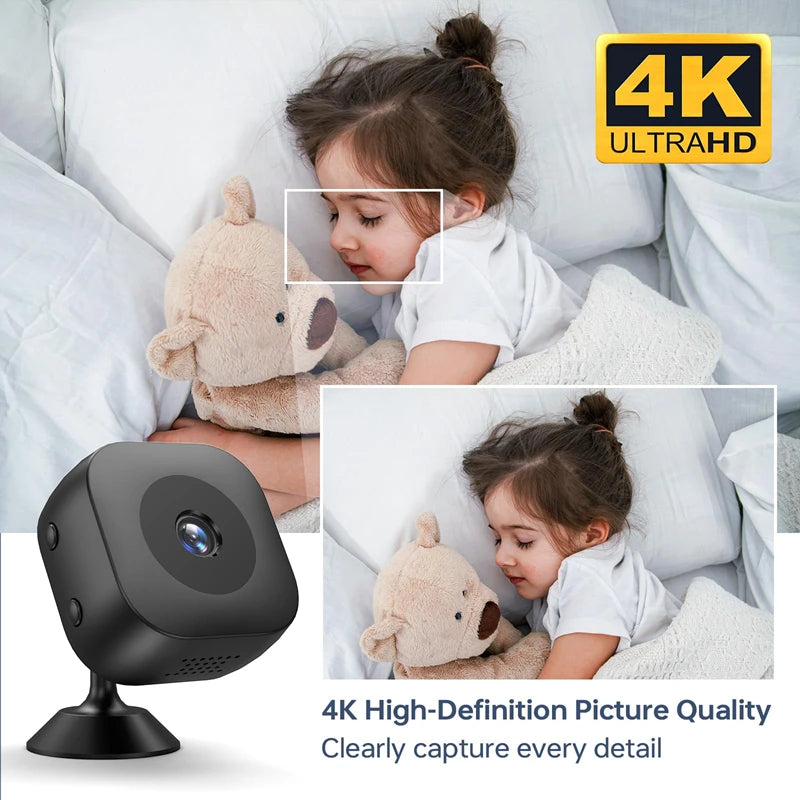 Simples Market Smart 4K mini camera with night vision on a black stand beside a sleeping child and teddy bear.