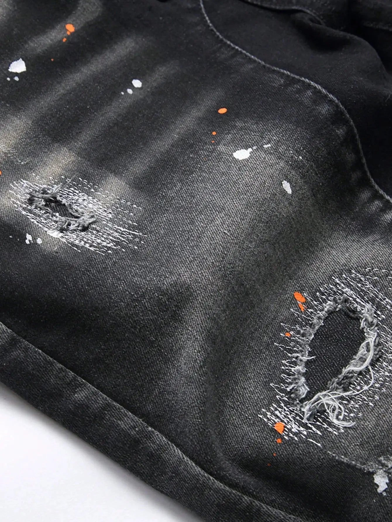 Men's knee-length denim shorts with ripped knees, dark wash, and orange paint-splatter accents