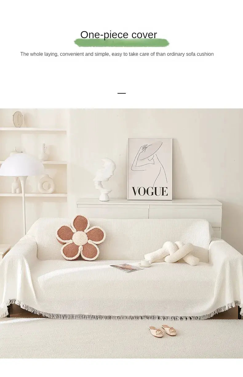 Sofa cover in cream knit wind-cotton yarn with full-coverage protection on a white sofa, fringe edge visible.