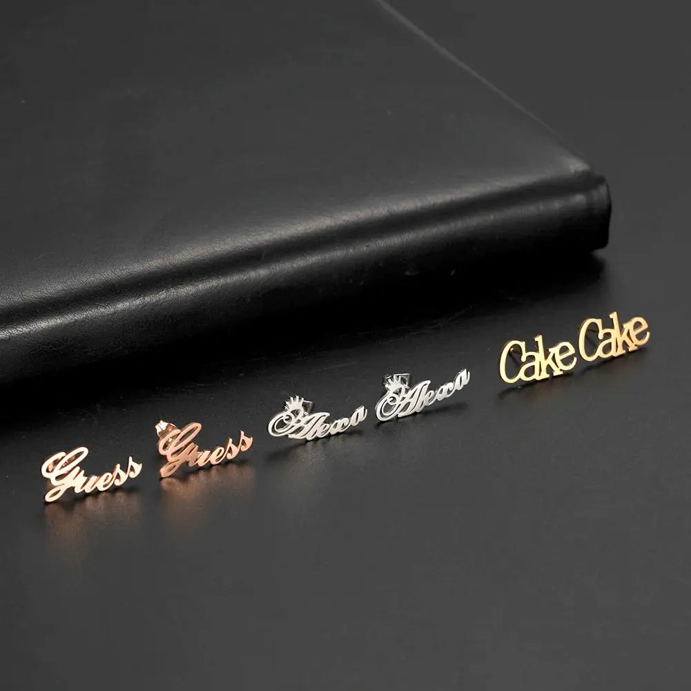 Script-logo stud earrings in rose gold, silver, and gold tones; set of five with Guess and Cake Cake branding.