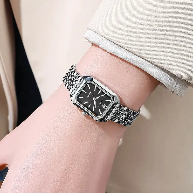 Luxury women's rectangular quartz watch with black dial and stainless steel bracelet worn on wrist
