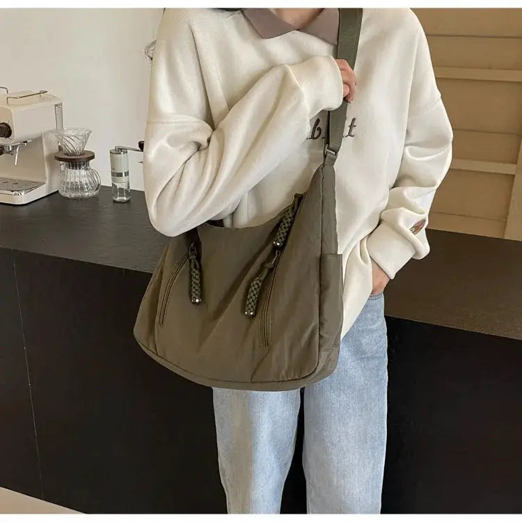 Trendy olive-brown soft-cloth shoulder bag with dual front zip pockets and tasseled pulls, crossbody strap