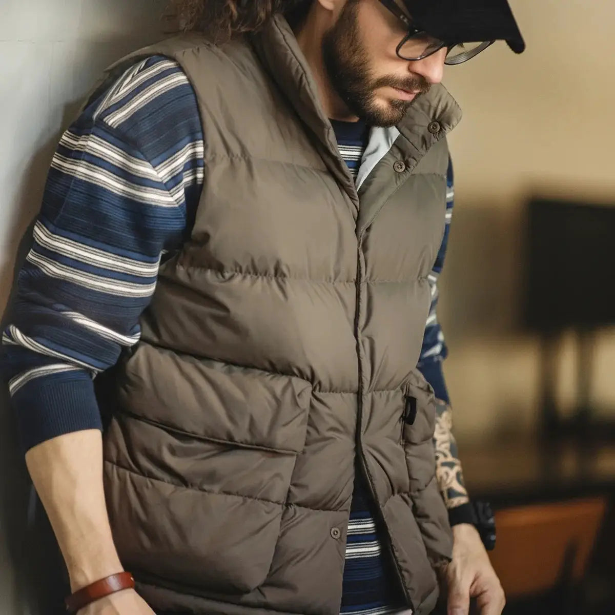 Maden men's taupe down vest with stand-up collar and double-side pockets over a blue striped sweater