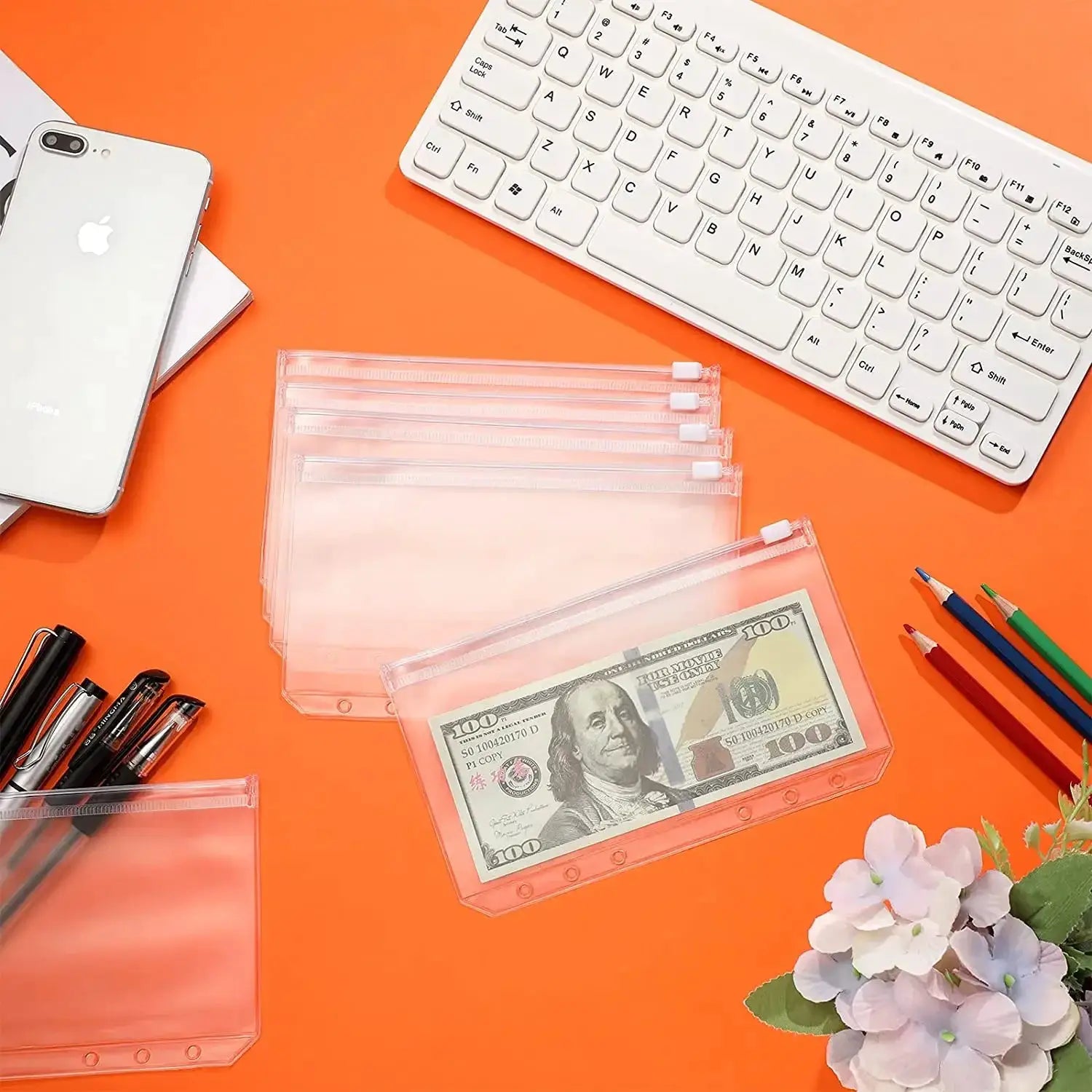 Clear PVC zipper binder pouches for notebooks, stacked with cash inside, on an orange desk.