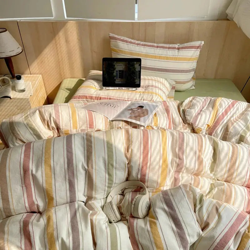 100% cotton striped bedding set with duvet cover and pillowcases on a bed in pastel pink, yellow, beige tones.
