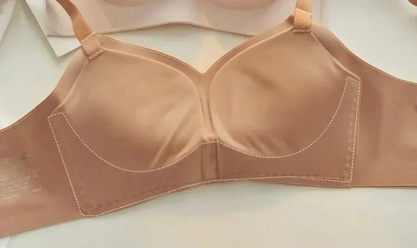 Nude molded-cup bra with thickened cups, peach fabric and white stitching, adjustable straps.