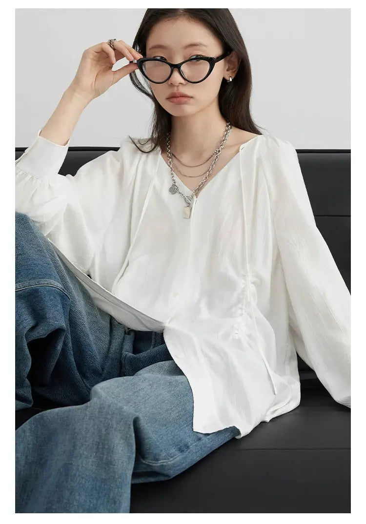 Women's white loose lace-up shirt with V-neck and raglan long sleeves, worn with jeans by a model