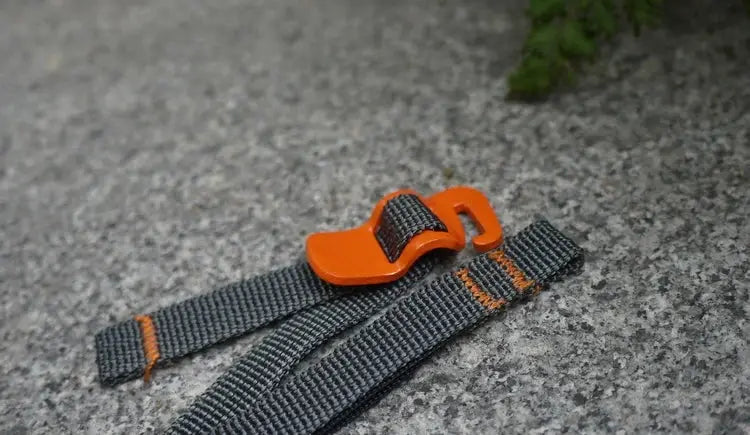 Luggage strap with orange quick-release buckle on gray nylon webbing