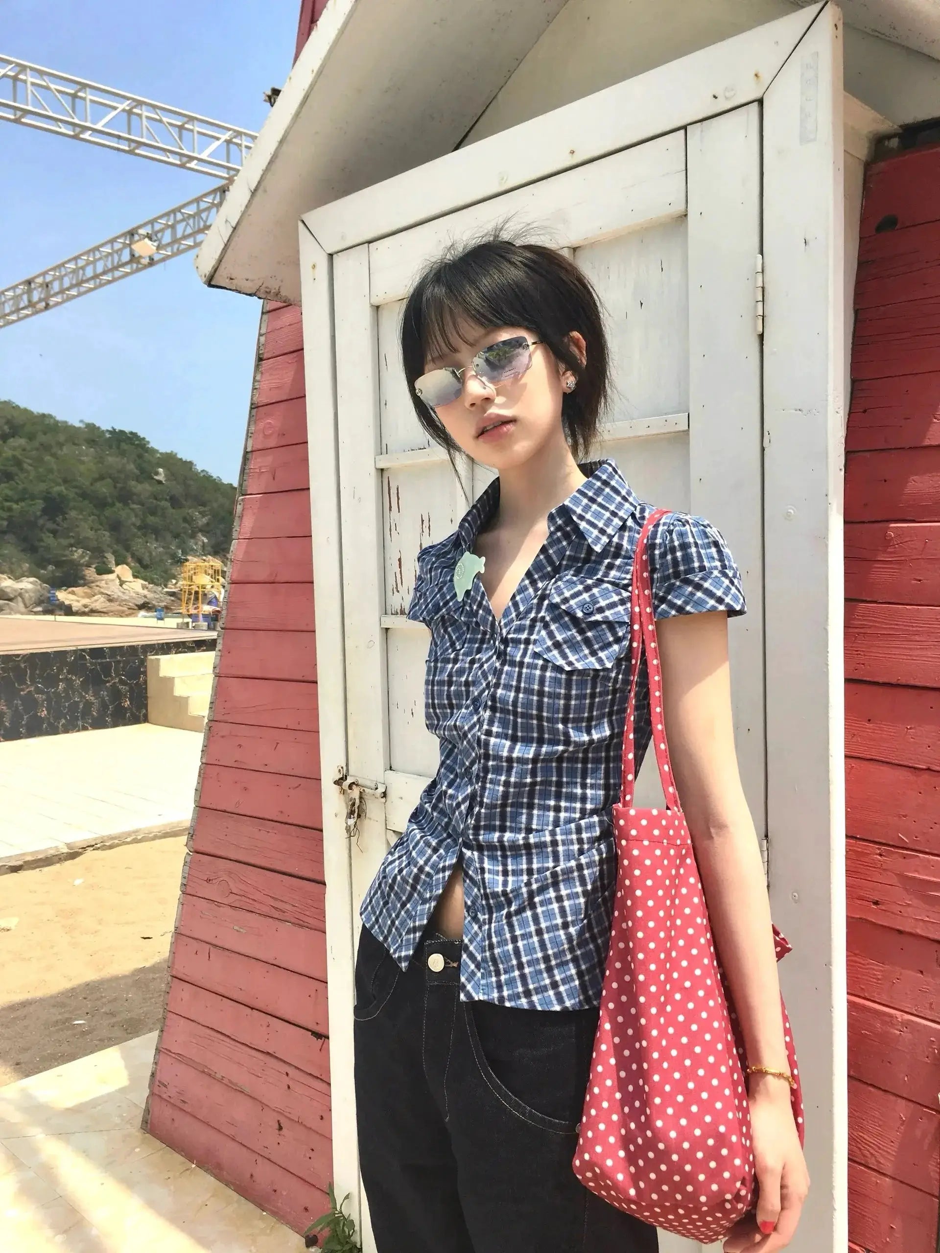 Blue plaid short-sleeve shirt with red polka-dot tote at a beachside location