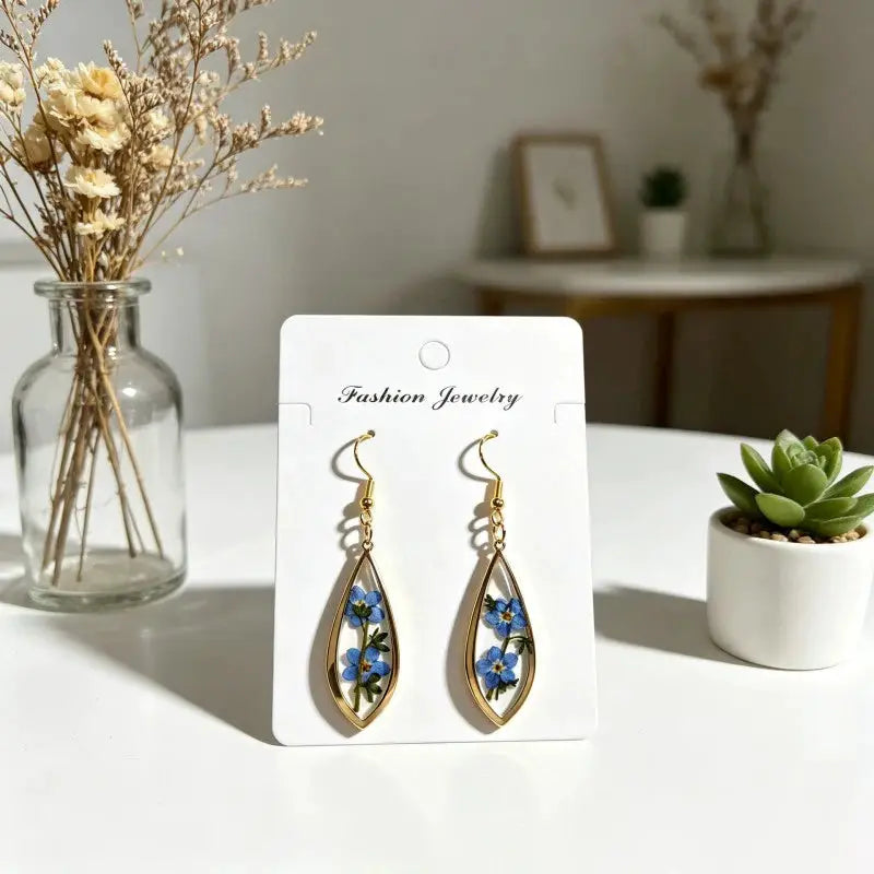Pair of teardrop epoxy resin earrings with blue pressed flowers in a gold-tone frame