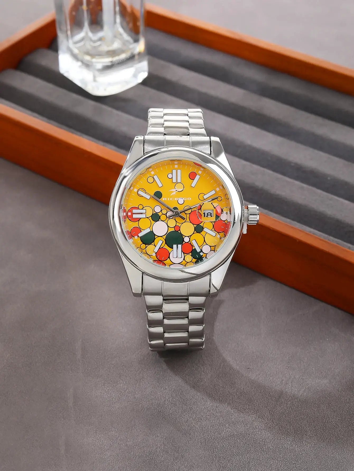 Men's stainless steel quartz watch with a vivid yellow dial featuring colorful circles, date window, and metal bracelet.