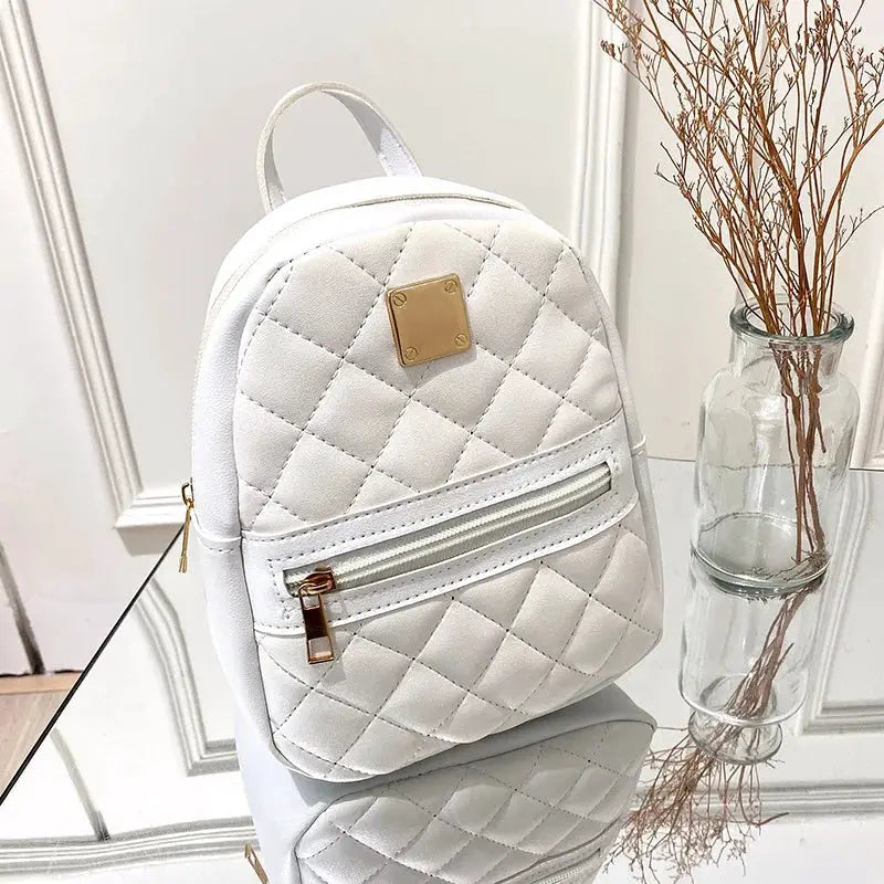 White quilted backpack with gold-tone hardware, front zip pocket, top handle