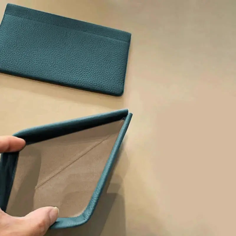 Teal artificial leather long wallet with pebbled texture and beige interior, opened to show card/ID slots.