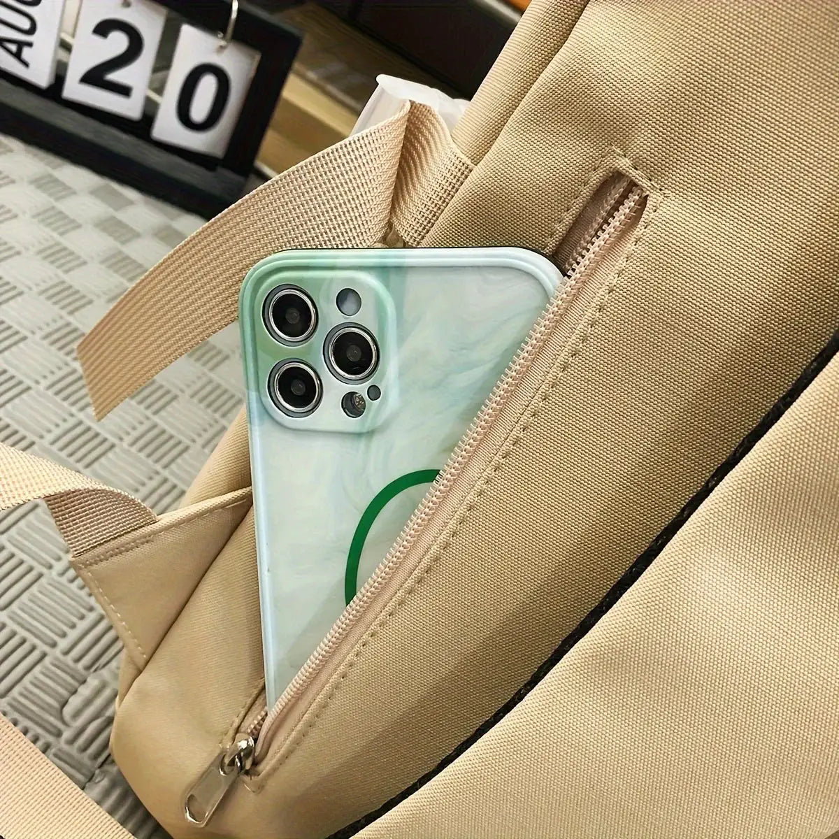 Simple large-capacity sports travel backpack in beige fabric with front zip pocket holding a smartphone