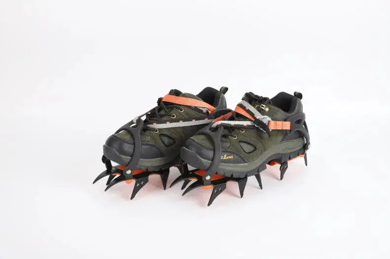 Pair of 12-tooth ice crampons with orange straps, worn on green hiking shoes, stainless steel spikes.