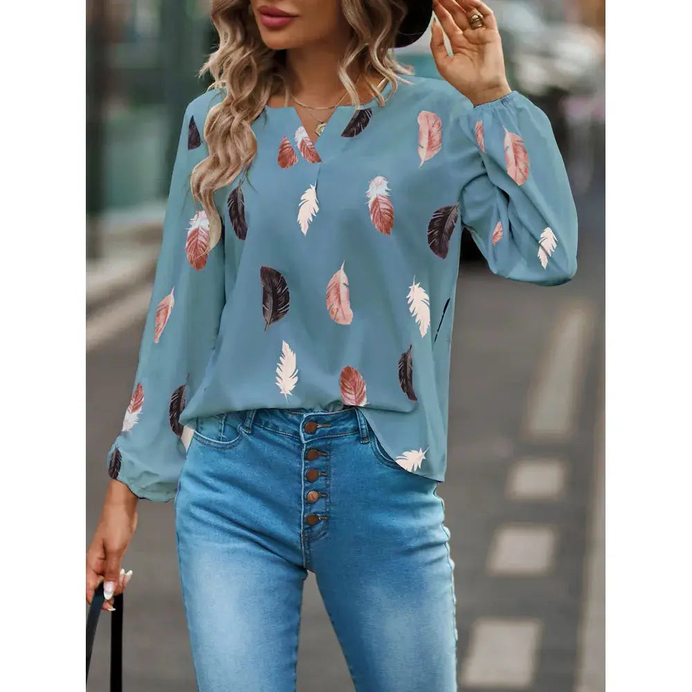 Blue feather-pattern chiffon blouse with long sleeves worn by a model, paired with denim jeans.