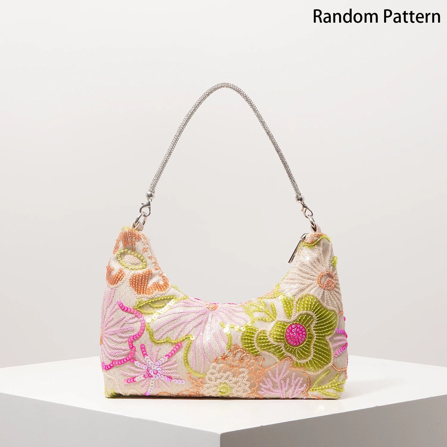Shoulder bag in pale pink with colorful embroidered floral pattern and silver chain strap.