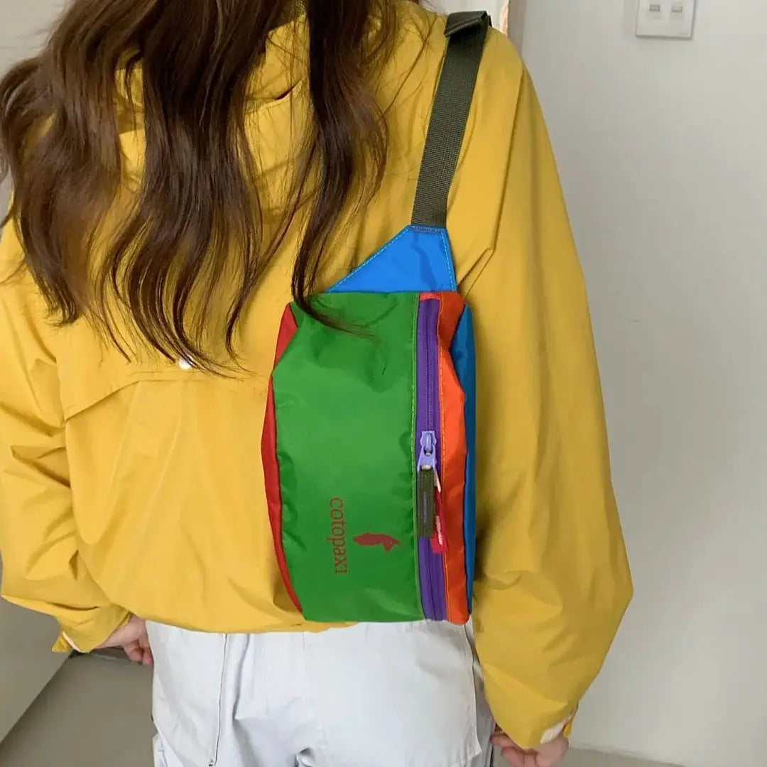 Crossbody waist bag in green with blue top and purple zipper, red side panels; camel emblem logo.