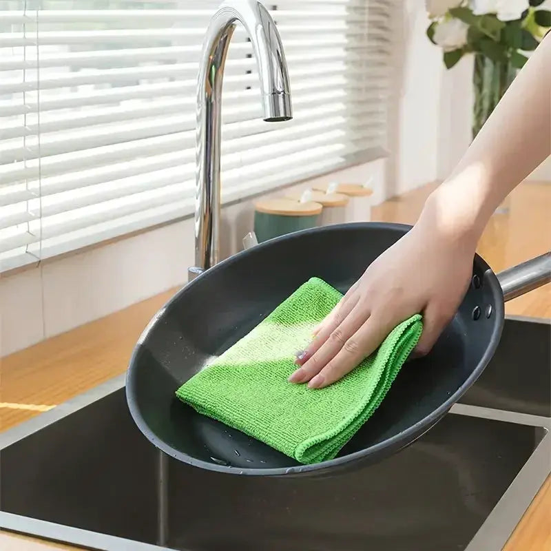 Microfiber dishcloth, green, used to wipe a pan in a kitchen