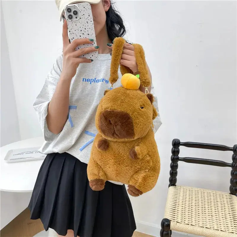 Plush capybara backpack crossbody bag in brown with a yellow fruit accent