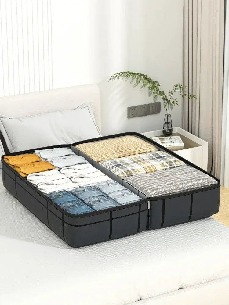 Foldable travel storage bag, black, with two compartments, opened on a bed and filled with folded clothes.