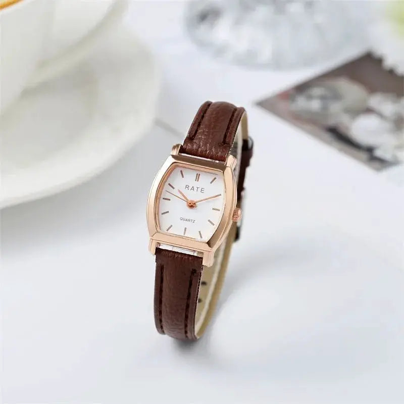 Women's quartz watch with brown leather strap, rose-gold case, and white dial.