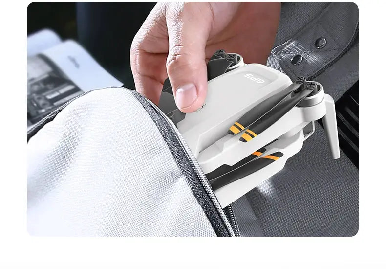 Simples Market L106-1PRO folding GPS drone with 4K camera, white quadcopter being placed into a backpack.