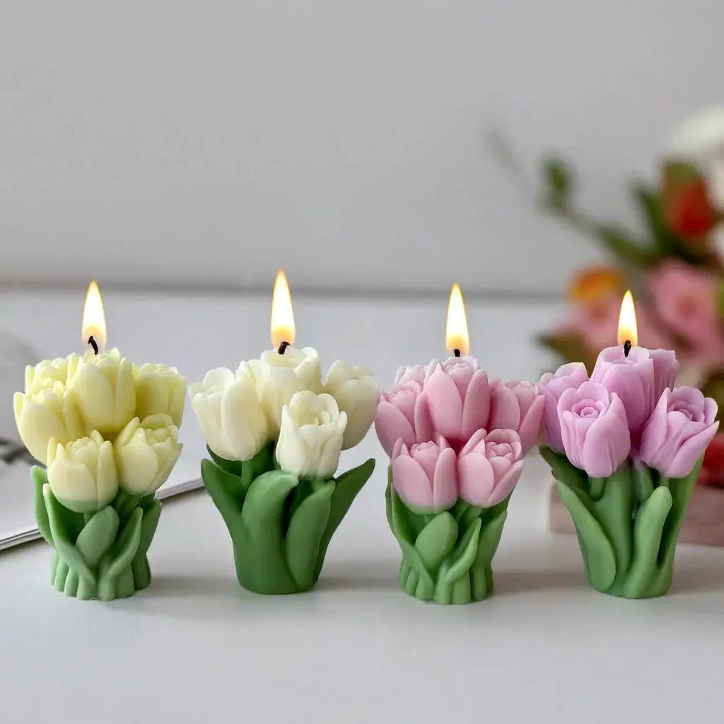 Four tulip-shaped silicone candle molds in cream, white, pink and lavender with lit wicks and green stems.