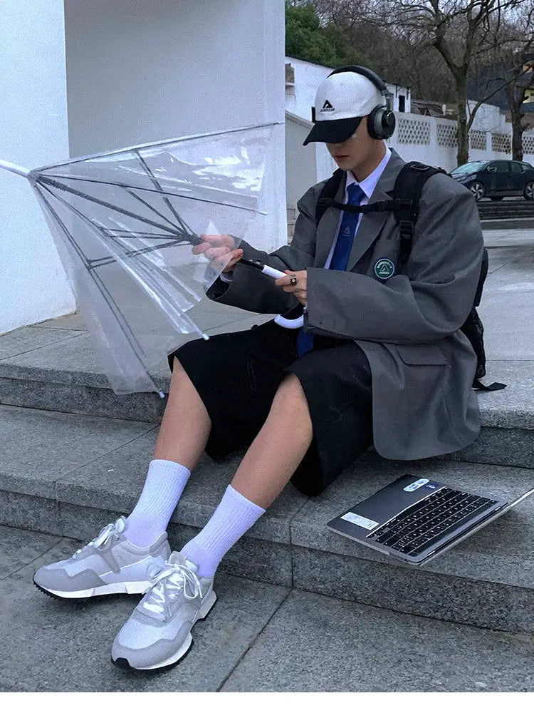 Mauroicardi men's loose black shorts with gray blazer, white sneakers, and Adidas cap on steps with umbrella