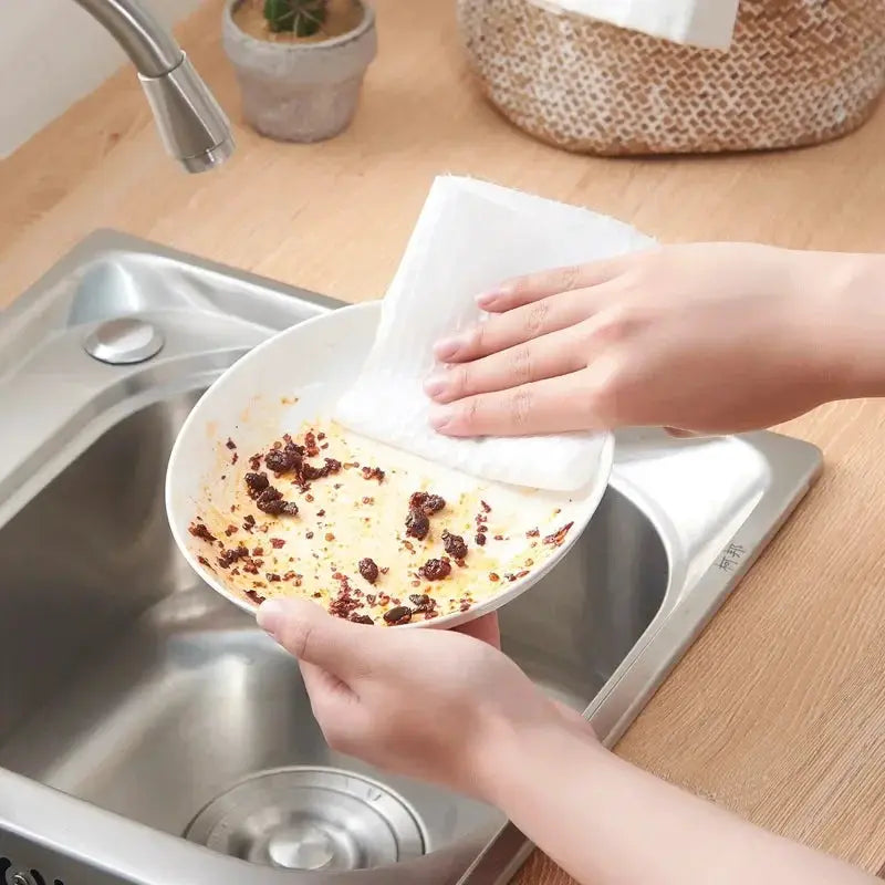 Kitchen disposable non-woven white cleaning cloth wiping a bowl at the sink