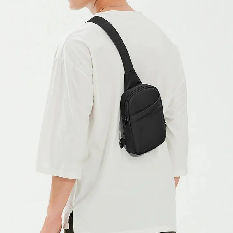 2-in-1 waist bag and chest bag in black worn crossbody by man, small sling backpack style.