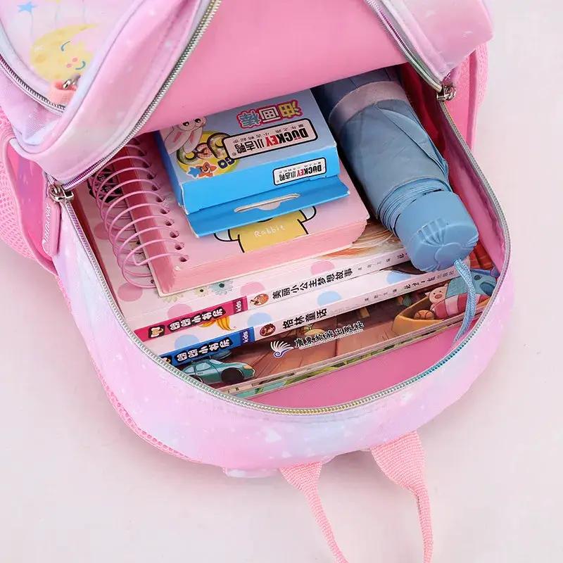 Pink unicorn backpack for girls filled with several books, notebooks, and a blue water bottle.