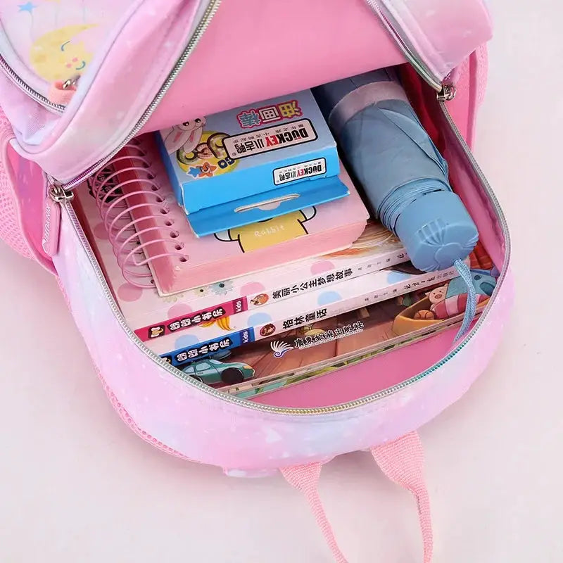 Unicorn backpack for girls pink cartoon design by Simples Market opened with notebooks, books and a blue water bottle