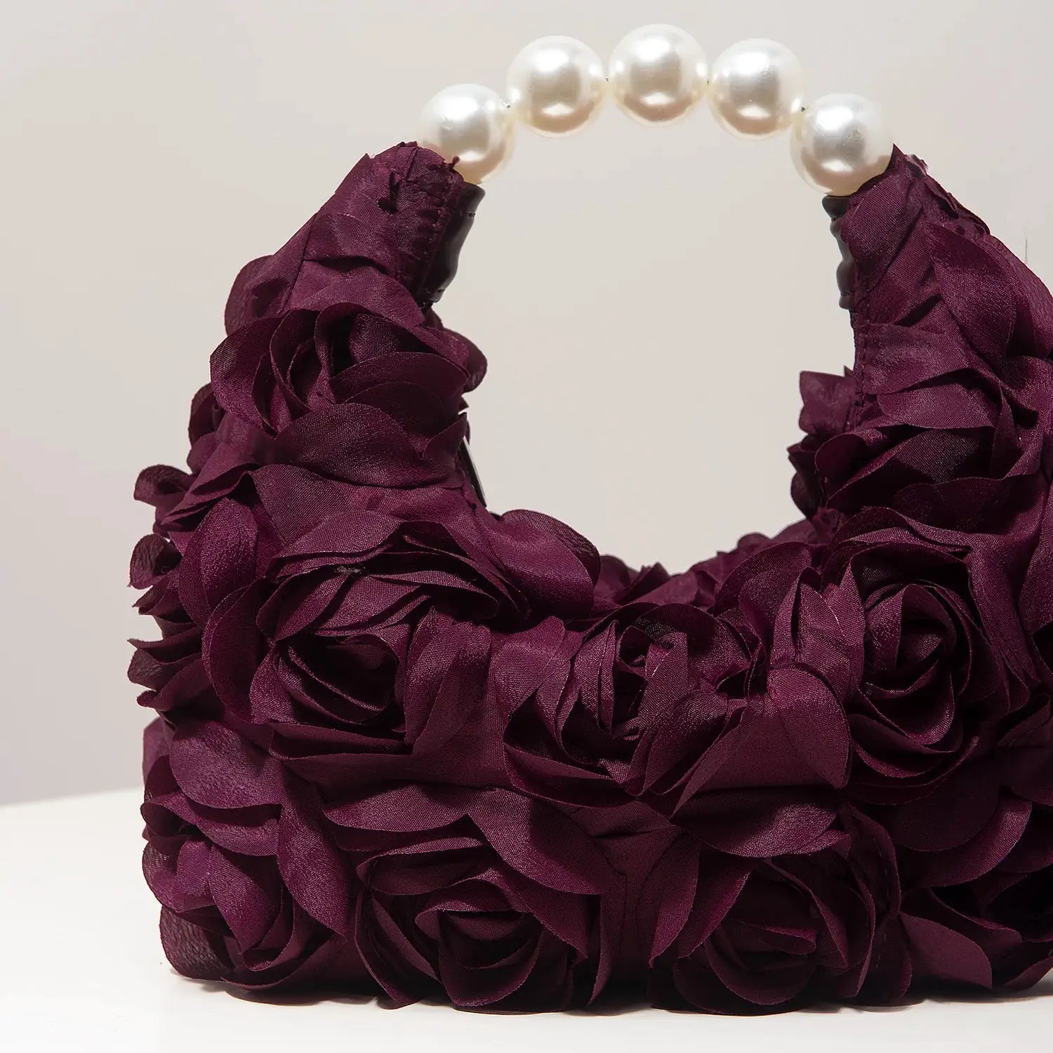 Purple floral rosette clutch with pearl bead handle by Simples Market
