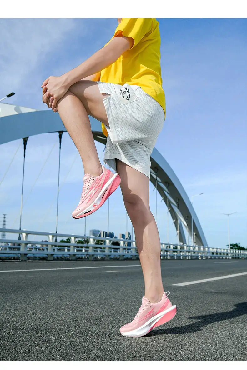 Pair of pink running shoes with white soles worn by a model in a yellow shirt on a bridge
