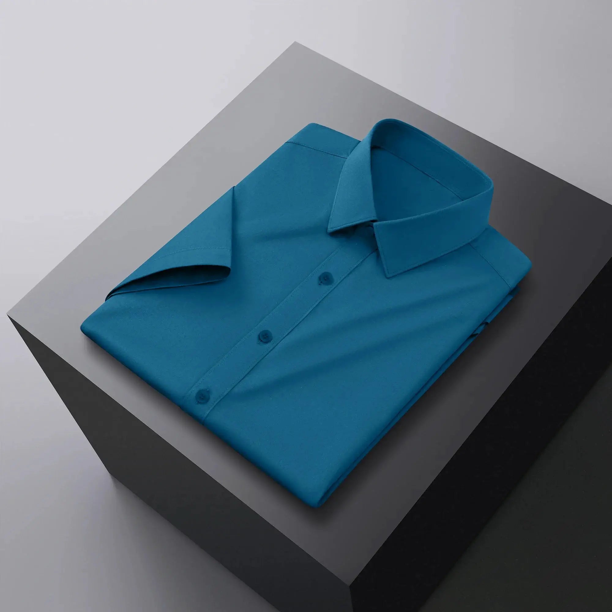 Men's blue solid-color business casual short-sleeve shirt neatly folded on a geometric backdrop