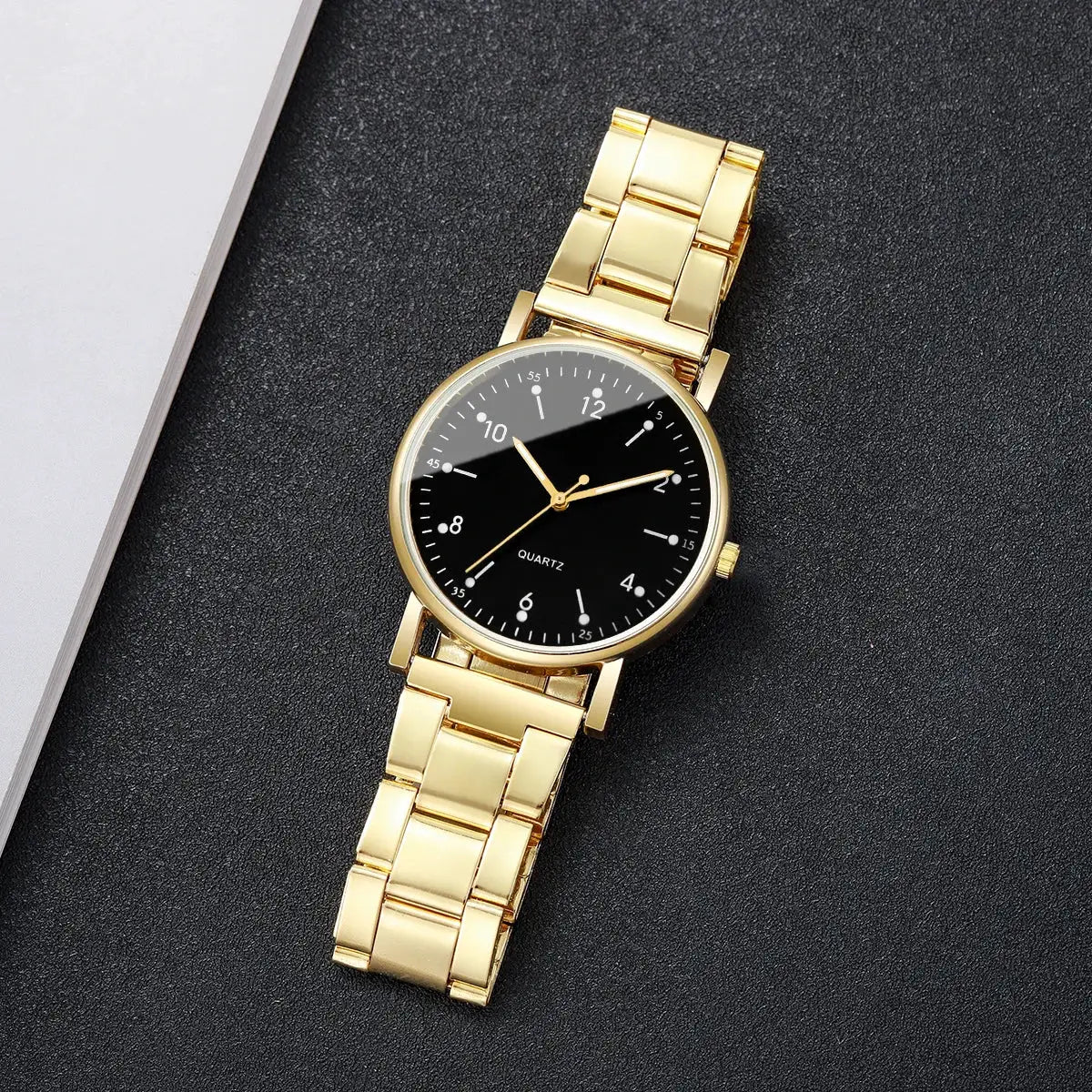 Gold-tone women's quartz wristwatch with black dial and white Arabic numerals on a metal link bracelet