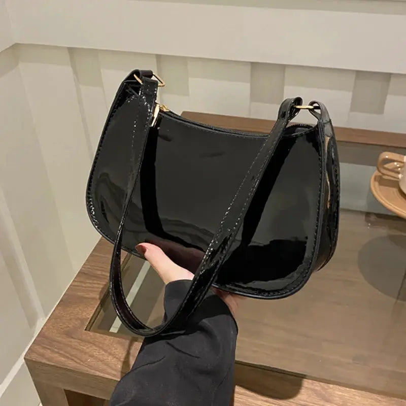 Black patent PU leather shoulder bag with a curved hobo silhouette and gold-tone hardware.