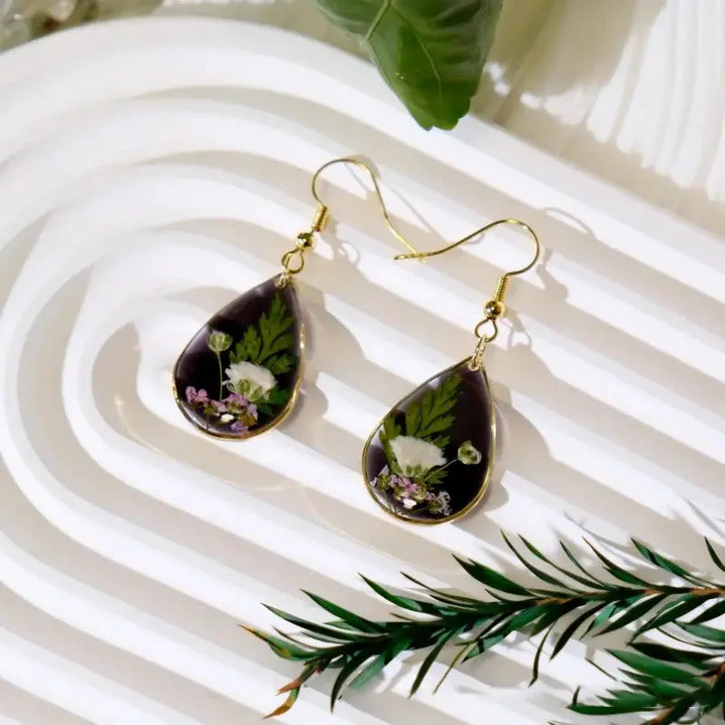 Pair of teardrop epoxy resin earrings with pressed flowers in purple frame and gold-tone hooks