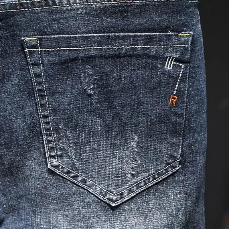 Men's blue distressed denim jeans with back pocket and orange R embroidery