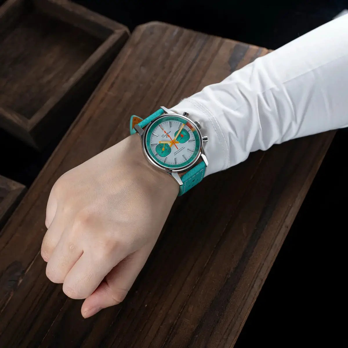 Sugess chronograph watch for men with turquoise strap and white dial with teal subdials.