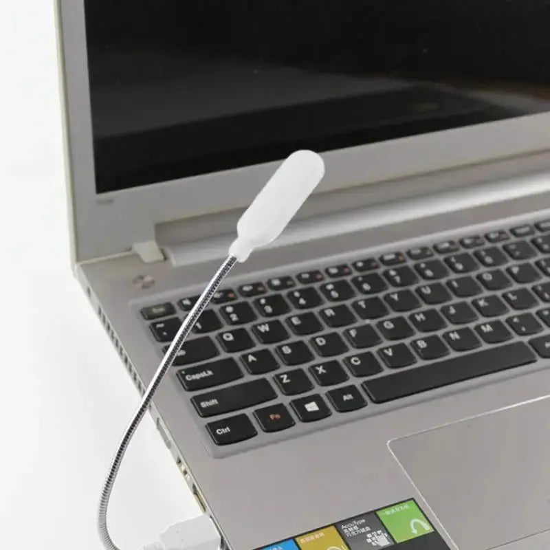 Portable USB book light with a flexible metal neck and white LED head plugged into a laptop